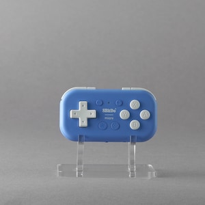 Könnte beinhalten: Ein blauer und weißer 8BitDo Micro-Gaming-Controller mit einem weißen Kreuz-Steuerkreuz, weißen Tasten und dem Text "8BitDo micro" auf der Vorderseite.