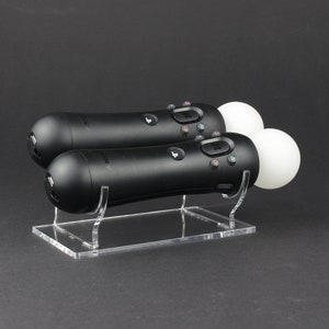 May include: Two black PlayStation VR Move controllers with white orbs on a clear acrylic stand.