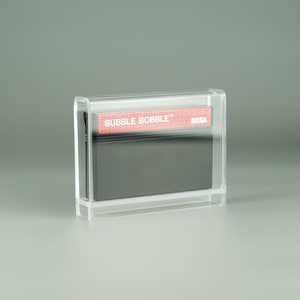 May include: A clear plastic case containing a black Sega Master System game cartridge with a red label that reads "BUBBLE BOBBLE" and "SEGA".