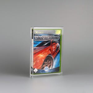 Könnte beinhalten: Eine transparente Kunststoffhülle mit einem Xbox-Spiel. Das Spielcover zeigt einen roten Sportwagen mit dem Titel "Need for Speed Underground". Das EA-Logo ist sichtbar. Die Hülle ist rechteckig und steht aufrecht.