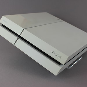 May include: A white PlayStation 4 console with the PlayStation logo on the front.