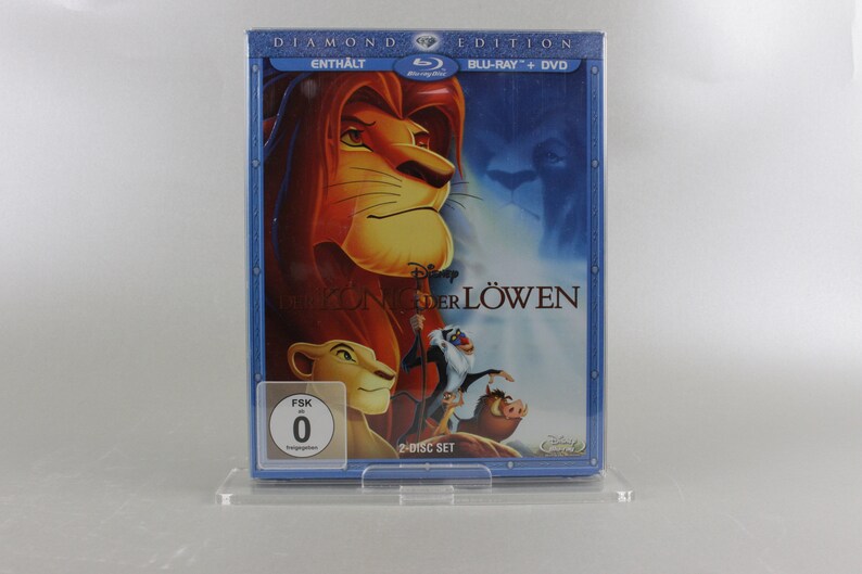 May include: A blue DVD case with a 2-disc set of the movie "The Lion King" in a diamond edition. The front of the case features a picture of Simba, the lion, with the text "DIAMOND EDITION" and "BLU-RAY + DVD" in white. The case also includes a FSK rating of 0.