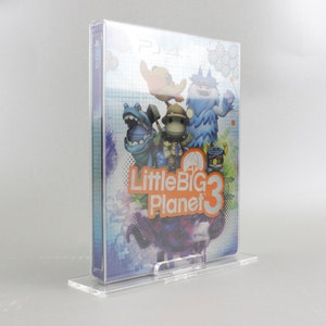 May include: A clear plastic case holds a video game for the Playstation 4. The game is LittleBigPlanet 3 and features colorful cartoon characters on the cover.
