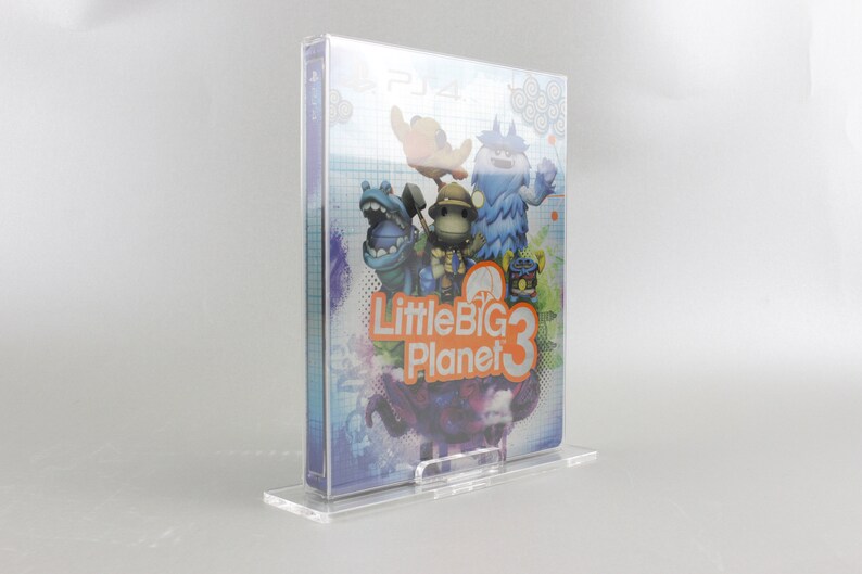May include: A clear plastic case holds a video game for the Playstation 4. The game is LittleBigPlanet 3 and features colorful cartoon characters on the cover.