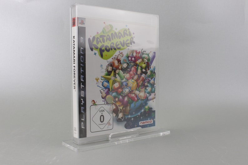 May include: A clear plastic case holds a video game for the Playstation 3. The game is Katamari Forever. The cover art features a colorful cartoon image of a large ball with many smaller balls attached to it. The game is rated 0 by the USK.
