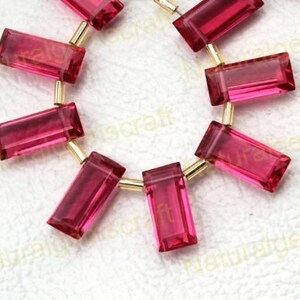 May include: A strand of pink faceted gemstone beads with gold-toned connectors. The beads are rectangular in shape and have a glossy finish.