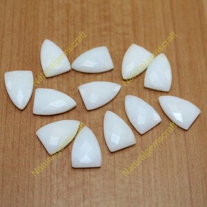 Peut inclure: Dix cabochons de pierres précieuses facettées de forme triangulaire et de couleur blanche. Les cabochons mesurent environ 2,5 cm de long et 1,25 cm de large.