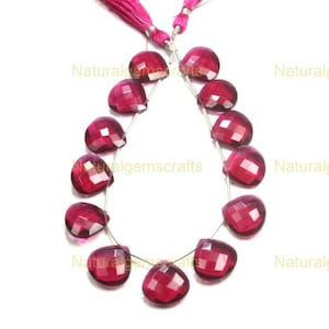 May include: A strand of 14 faceted gemstone beads in a deep pink color. The beads are shaped like teardrops and are strung on a silver wire.