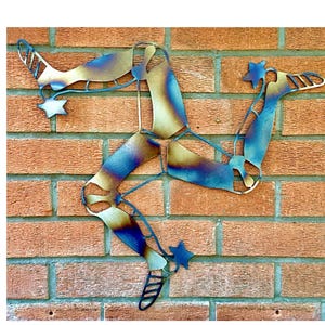 May include: A metal sculpture of the three legs of Mann, a symbol of the Isle of Man, mounted on a brick wall. The sculpture is made of metal that has been heat-treated to create a blue and gold colour gradient.