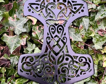 May include: Black metal wall decor in the shape of a hammer with intricate Celtic knotwork designs.