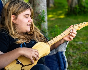 the Boondocker Maple + Spruce  Dulcitar 4 string Musical String Instrument. Small, lightweight, great for travel. Anyone can play!