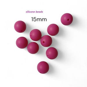 May include: Deep pink silicone beads, each 15mm in diameter, are scattered on a white background. The text "silicone beads" and "15mm" are visible. The beads have a smooth finish and a small hole through the center.