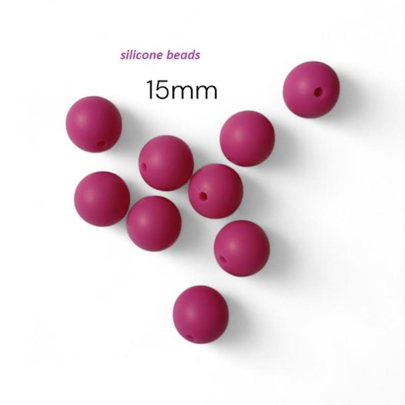 May include: Deep pink silicone beads, each 15mm in diameter, are scattered on a white background. The text "silicone beads" and "15mm" are visible. The beads have a smooth finish and a small hole through the center.