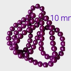 May include: A strand of deep purple beads, each 10 mm in diameter, arranged in a decorative pattern. The beads have a glossy finish and are strung together. The text "10 mm" is visible in the image.