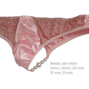 May include: Pale pink satin and lace underwear with a thong back. The front panel is satin, and the sides are lace. A string of white beads decorates the thong. The text "Beads, set white" and measurements are visible.
