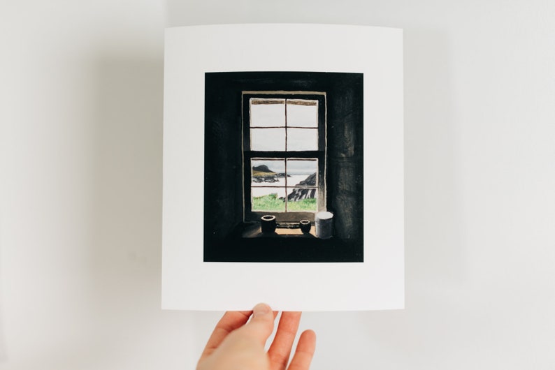 May include: A framed print of a window overlooking a coastal landscape. The window is divided into panes, with a view of the sea, green grass, and rocky cliffs. Two small pots and a white container sit on the windowsill.