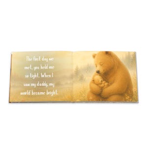 May include: An open book with a heartwarming illustration of a bear hugging a baby bear. The text reads, "The first day we met, you held me so tight. When I saw my daddy, my world became bright."