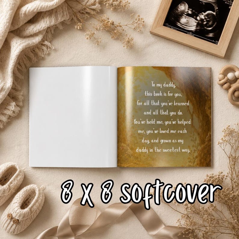 May include: An open softcover book with the text "To my daddy, this book is for you..." on a gold-toned page. The book is 8 x 8 inches. The image also shows baby shoes, a framed sonogram, and a wooden toy.