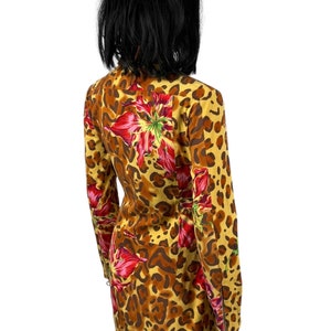 May include: A yellow, brown and red dress with a leopard print and floral pattern. The dress has long sleeves and a zip on the cuffs.