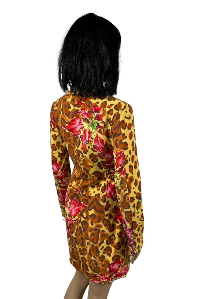 May include: A yellow, brown and red dress with a leopard print and floral pattern. The dress has long sleeves and a zip on the cuffs.