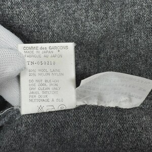 以下が含まれることがあります： 黒い持ち手と「But First, Coffee」のテキストが黒い太字で書かれた白いセラミックマグ。マグカップはぼやけた背景に置かれており、居心地の良い環境を示唆しています。