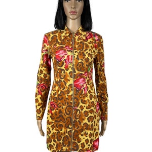 May include: A yellow, brown and red long-sleeved dress with a leopard print and floral accents. The dress has a zip down the front.