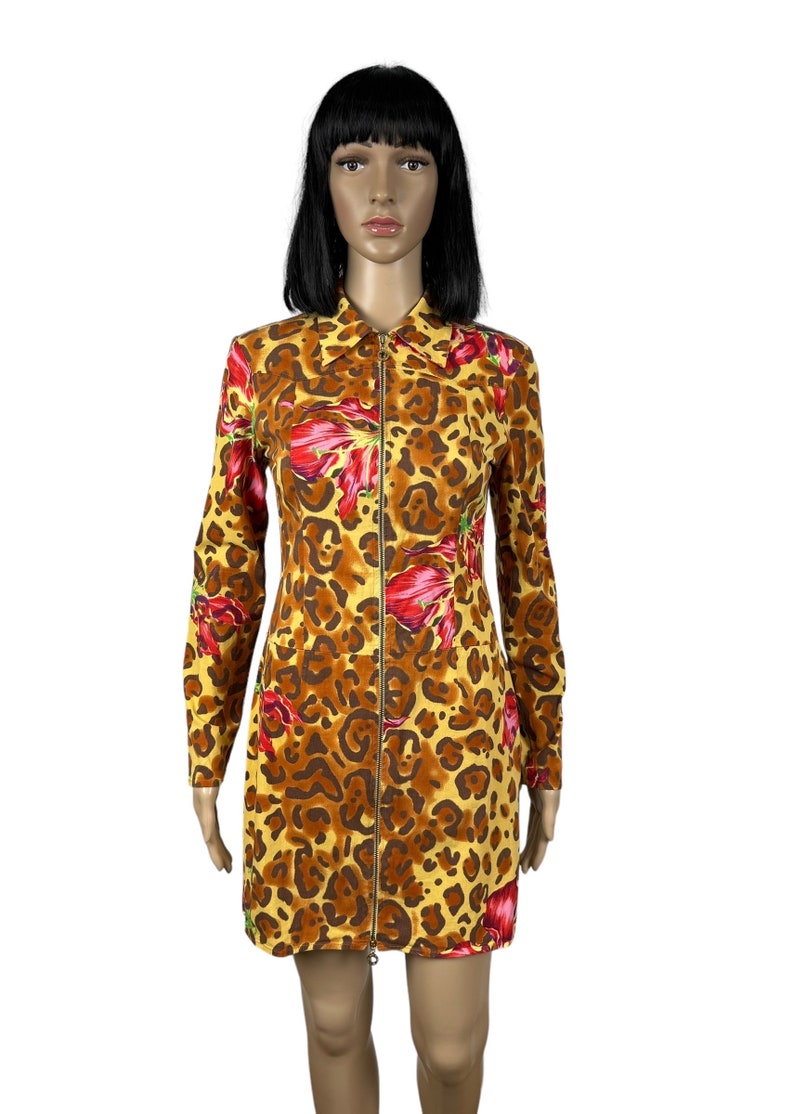 May include: A yellow, brown and red long-sleeved dress with a leopard print and floral accents. The dress has a zip down the front.