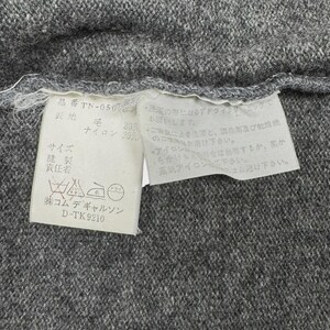 以下が含まれることがあります： グレーの生地のクローズアップ。白いタグが取り付けられています。タグには日本語のテキストとケアマークが含まれています。生地はウールとナイロンの混紡のようです。タグには洗濯とアイロンがけの説明が含まれています。