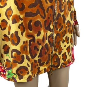 May include: A short-sleeved dress with a leopard print pattern in shades of brown, orange, and yellow. The dress has a front zipper closure and a floral print detail at the bottom.