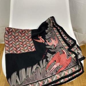 Könnte beinhalten: Schwarzer Seidenschal mit geometrischem Muster und rosa und grünen Vögeln. Der Schal hat einen Rand mit einem sich wiederholenden Muster aus rosa, grünen und schwarzen Dreiecken. Der Text "SALVINI" ist auf den Schal gedruckt.