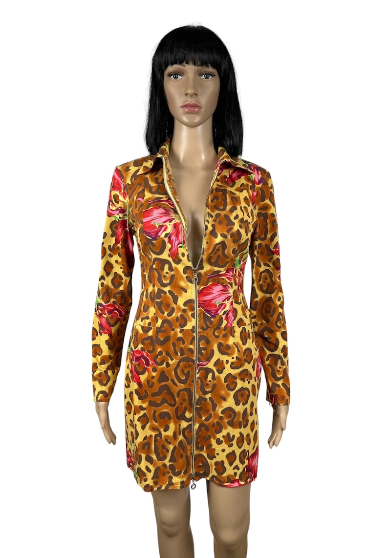 May include: A yellow, brown and red leopard print dress with a long sleeve and a zip down the front.