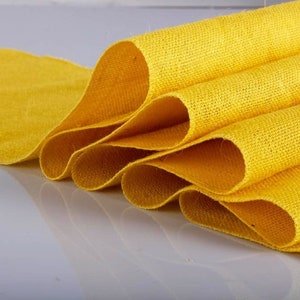 May include: A roll of yellow burlap fabric, folded and stacked, with a textured surface.