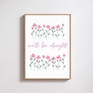 May include: A framed art print featuring pink flowers with green stems against a white background. The phrase "we'll be alright" is written in pink script below the flowers. The frame is a light brown color.
