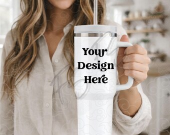 Puede incluir: Vaso blanco con asa y pajita, con el texto "Your Design Here" en negro. El vaso tiene tapa blanca y asa blanca. El fondo está borroso.