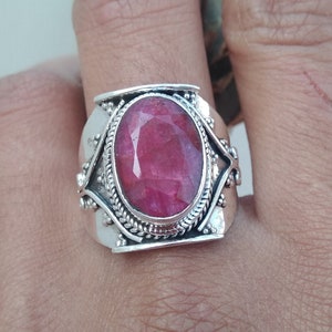 Op de afbeelding: Een zilveren ring met een grote, ovale, roze edelsteen gezet in een gedetailleerde zilveren band.