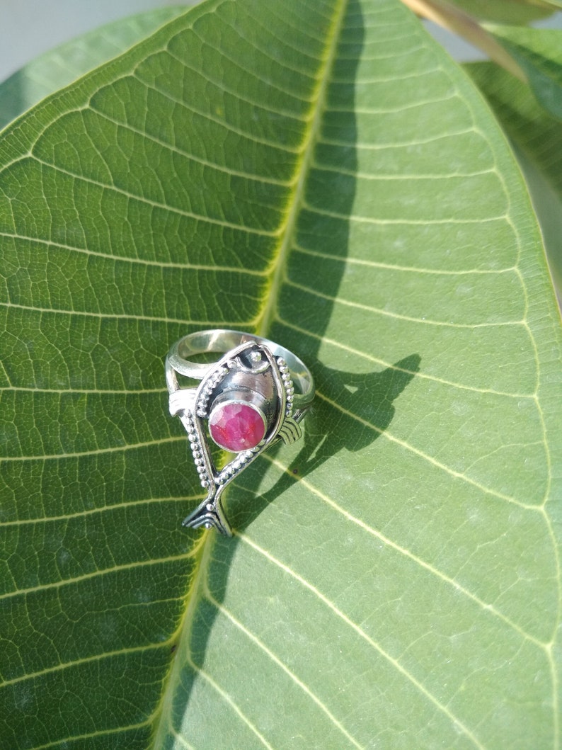 May include: A silver ring with a pink gemstone set in a fish design.