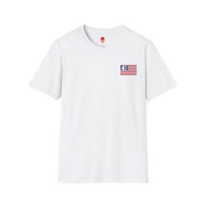 May include: White short-sleeved t-shirt with a small American flag on the left chest. The flag has the number "47" in blue on it.