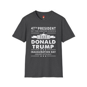 May include: Dark grey t-shirt with white text that reads "47th President of the United States Donald Trump" with a graphic of the White House and the text "Inauguration Day January 20th, 2025".