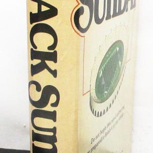 May include: A book titled "Black Sunday" by Thomas Harris. The cover is beige with black lettering and a stadium graphic. The author's name is printed at the bottom. The book is published by Putnam.