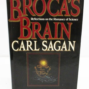 May include: A black book cover with the title "Broca's Brain: Reflections on the Romance of Science" by Carl Sagan. The cover features a gold outline of a face with a bright light above it.