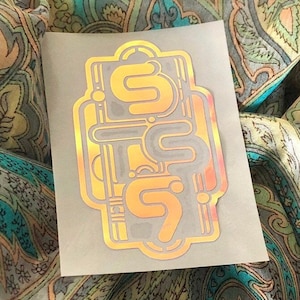 May include: A gold and silver sticker with the word "Sixty" written in a stylized font.