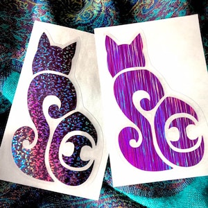May include: Two iridescent purple cat stickers. One sticker has a glitter finish and the other has a holographic finish.