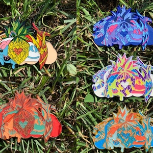 May include: Four enamel pins featuring a pineapple, a heart, and a cloud with a colorful, abstract design. The pins are in different color combinations: blue, pink, red, and orange.