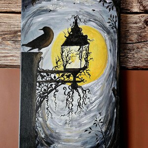 May include: An acrylic painting of a spooky scene featuring a black raven perched on a stone post, a glowing yellow moon, and a black lantern. Two orange pumpkins sit at the bottom. The artwork is on a wooden scroll.