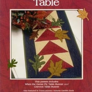 May include: A quilting pattern book cover featuring a colorful quilt design with a fall theme. The title of the book is "The Autumn Table" and the author is Lynette Jensen. The book is published by Thimbleberries.