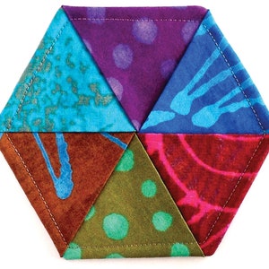 May include: A hexagonal coaster made from six colorful fabric triangles. The triangles are sewn together to create a geometric pattern. The fabric is a batik print with various colors and patterns, including blue, purple, red, green, and brown.