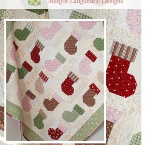 May include: A quilt pattern featuring a patchwork design of Christmas stockings in various colors and patterns, including red, green, brown, and pink. The quilt is titled "Stocking Stuffers" and includes the website "www.thepatternbasket.com".