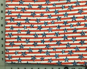 May include: Red and white striped fabric with blue stars printed on it. The fabric is measured with a ruler in inches.