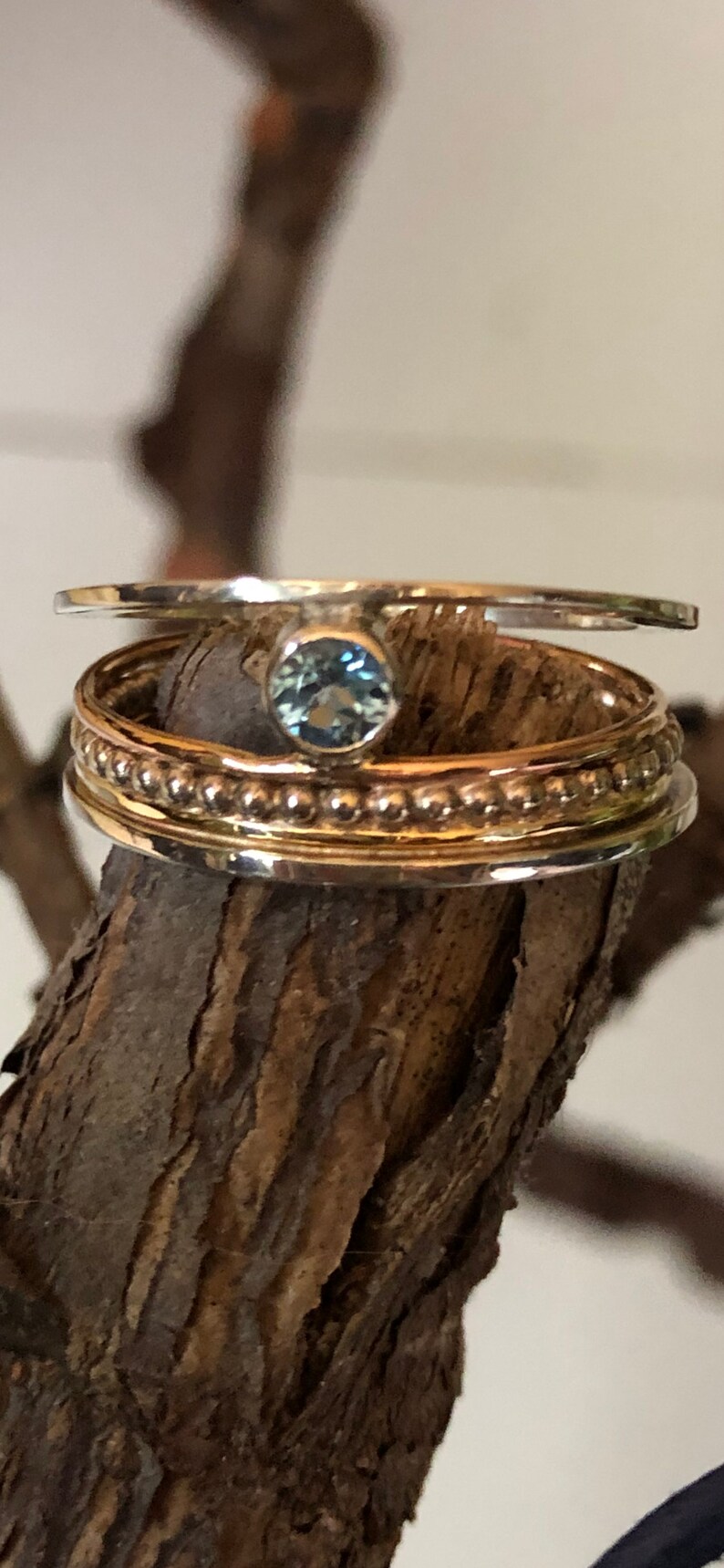 May include: A set of three silver rings with a blue gemstone in the center. The rings are stacked on top of each other and have a beaded design.