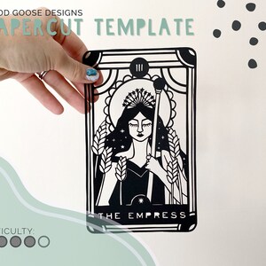 May include: Black and white papercut template of the Empress tarot card. The Empress is depicted as a woman wearing a crown and holding a staff. The card is labeled "III THE EMPRESS".
